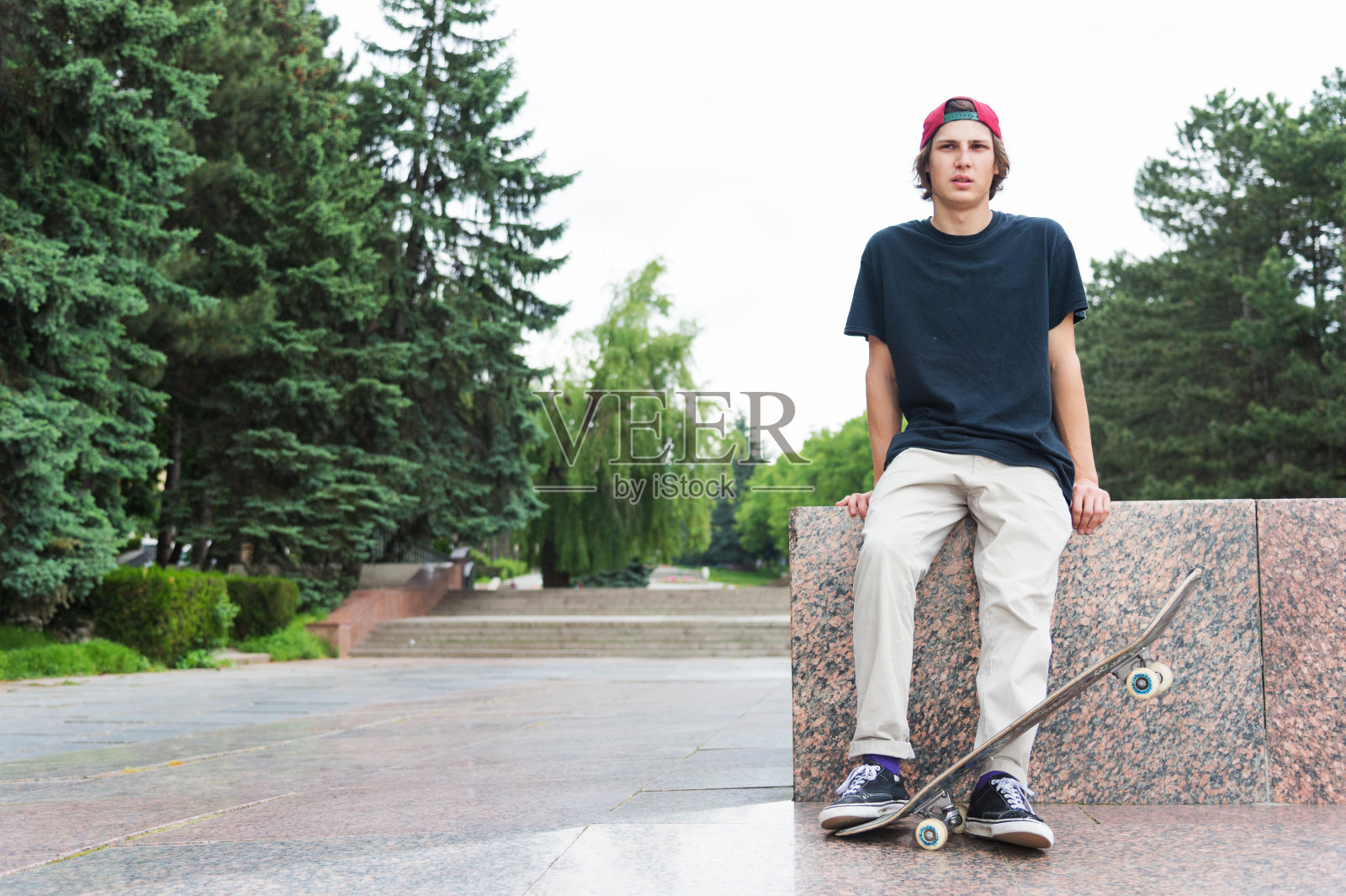 滑板手坐在他的背部和思考旁边的滑板照片摄影图片