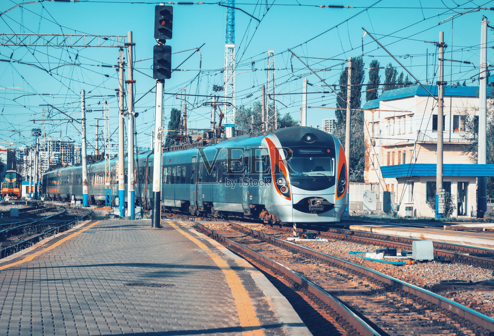 在欧洲，一列高速列车在日落时分到达火车站。火车站站台上的现代城际列车。铁路上有客运列车的工业景观。铁路运输照片摄影图片