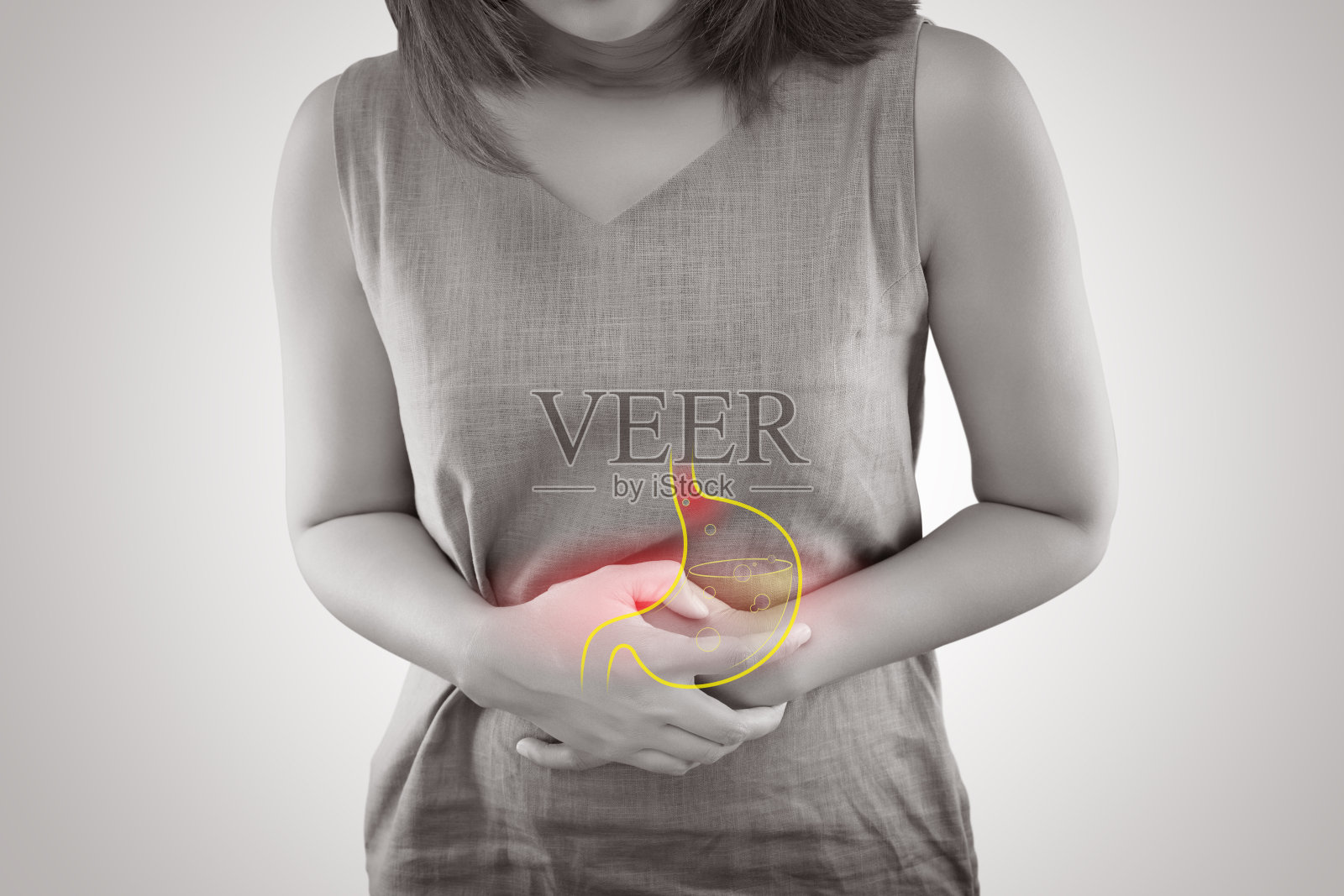 患有胃食管反流病或胃酸反流的女性站在灰色背景下，女性解剖学概念照片摄影图片