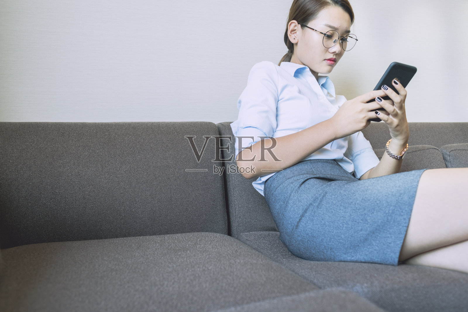 女人坐在沙发上使用智能手机的侧视图照片摄影图片