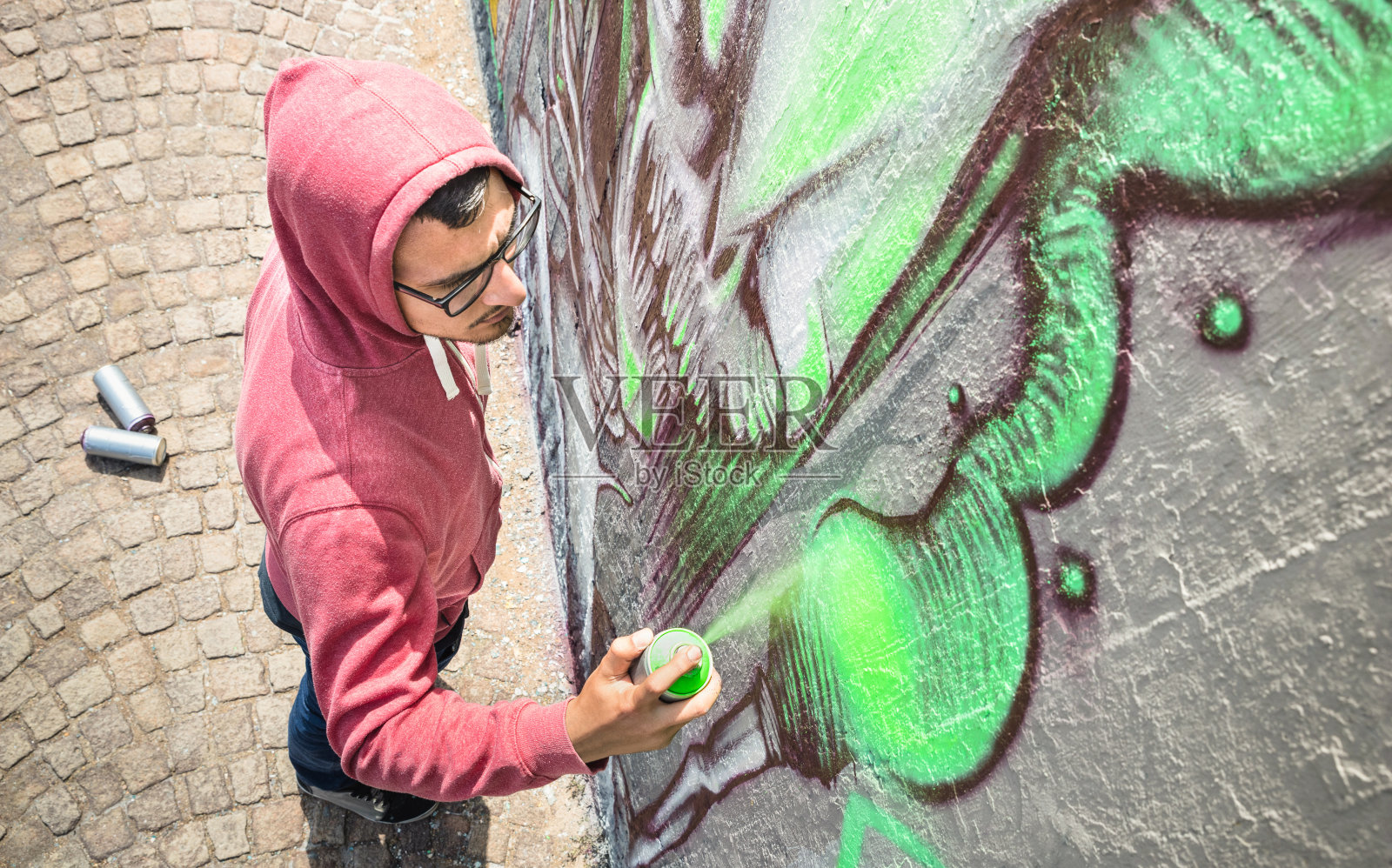 街头艺术家在普通的墙上画彩色涂鸦-现代艺术概念与城市人表演和准备活壁画与绿色气溶胶彩色喷雾-阳光明媚的下午中性过滤器照片摄影图片