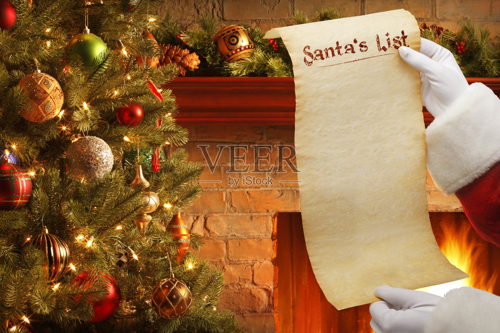 圣诞老人在圣诞树和壁炉前拿着空白名单照片摄影图片