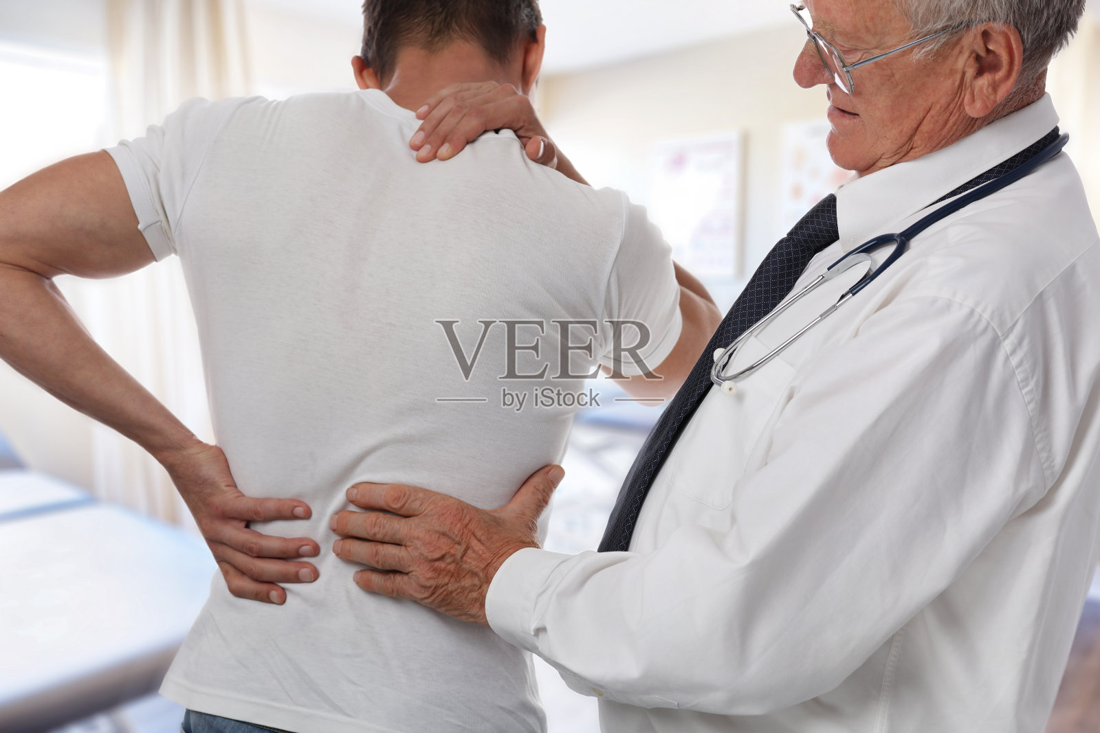 男医生和病人在体检时背部疼痛。照片摄影图片