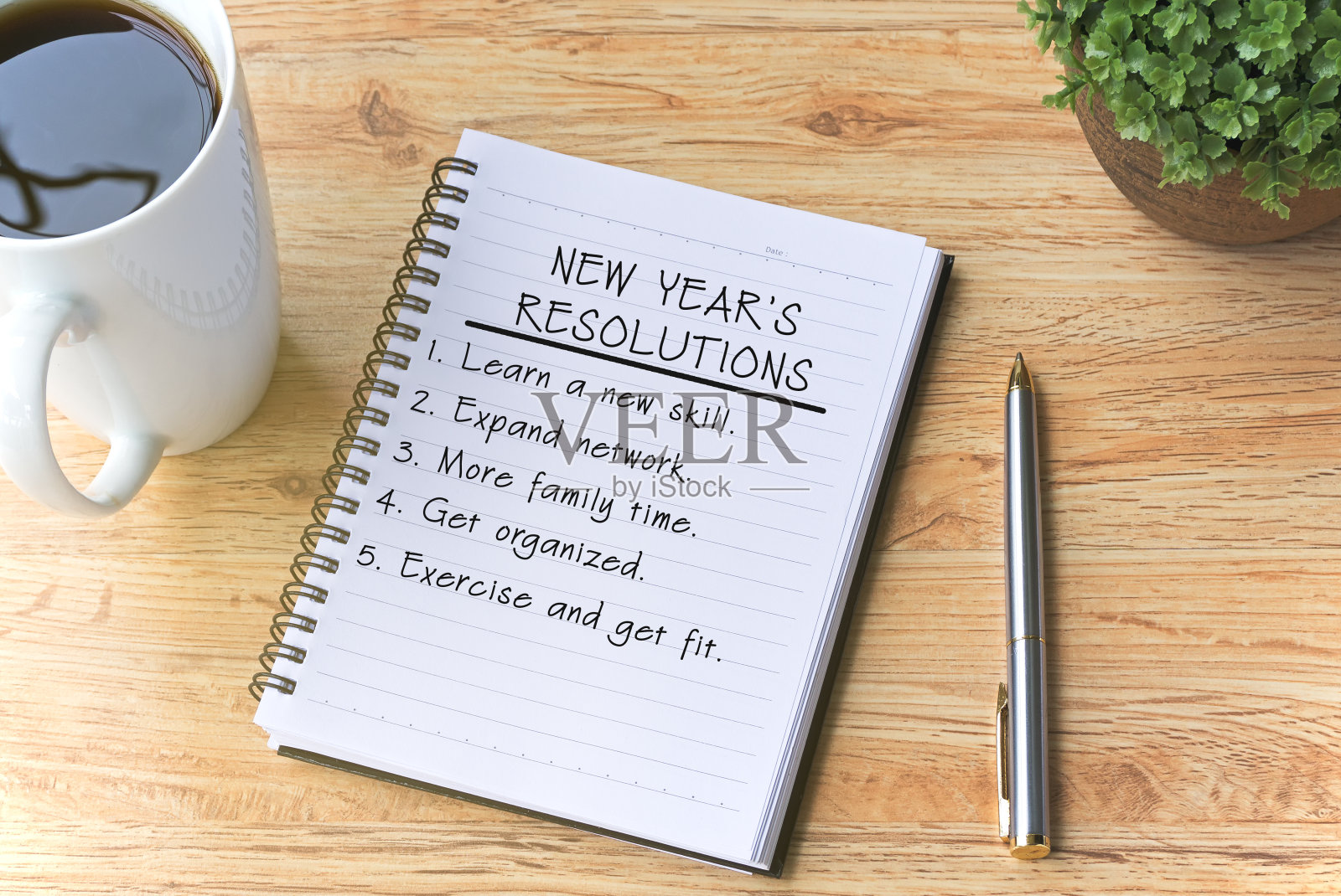 新年决心写在记事本上，用钢笔，咖啡和植物放在木桌上。插画图片素材