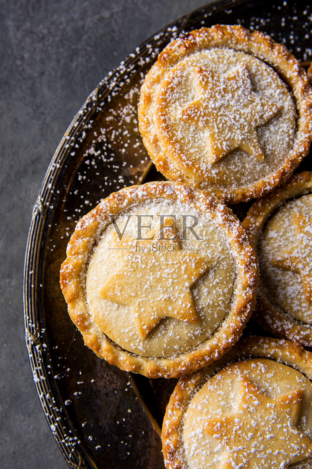 传统的英国圣诞糕点甜点家烤碎馅饼与苹果葡萄干坚果填充金色酥皮粉在复古金属板黑色混凝土背景俯视图照片摄影图片