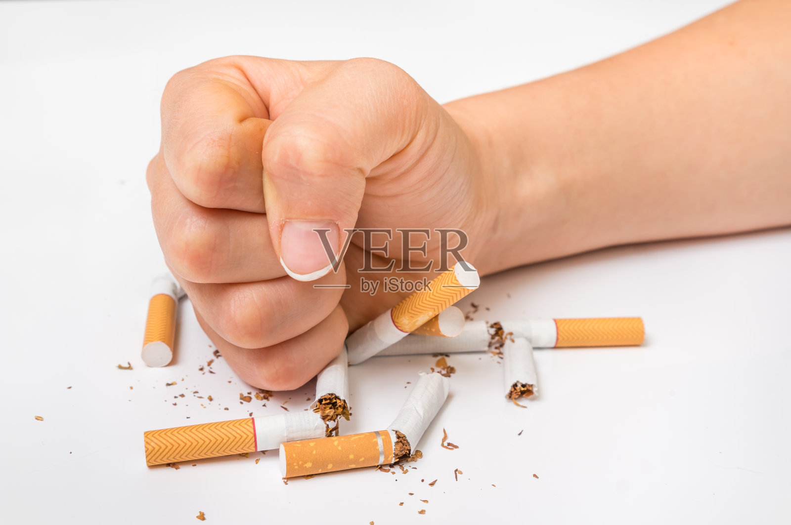 人的拳头和一堆破香烟-停止吸烟的概念照片摄影图片