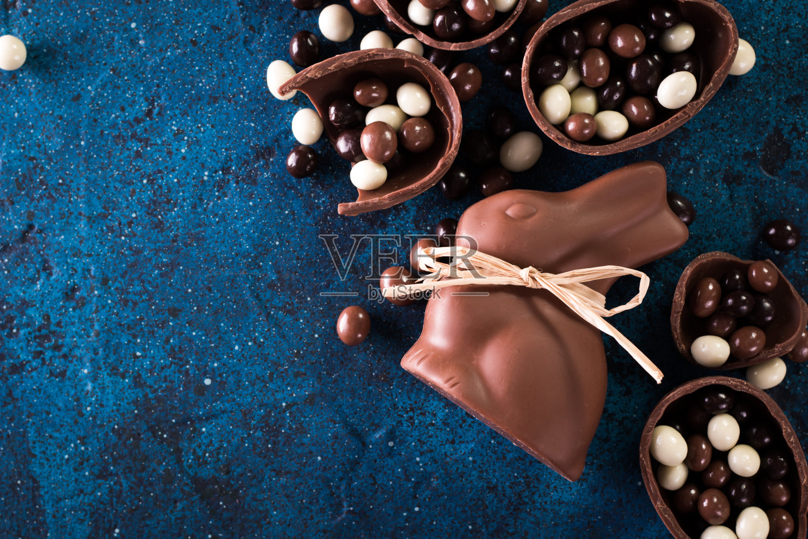 美味的巧克力复活节彩蛋，兔子和糖果在深蓝色的背景照片摄影图片