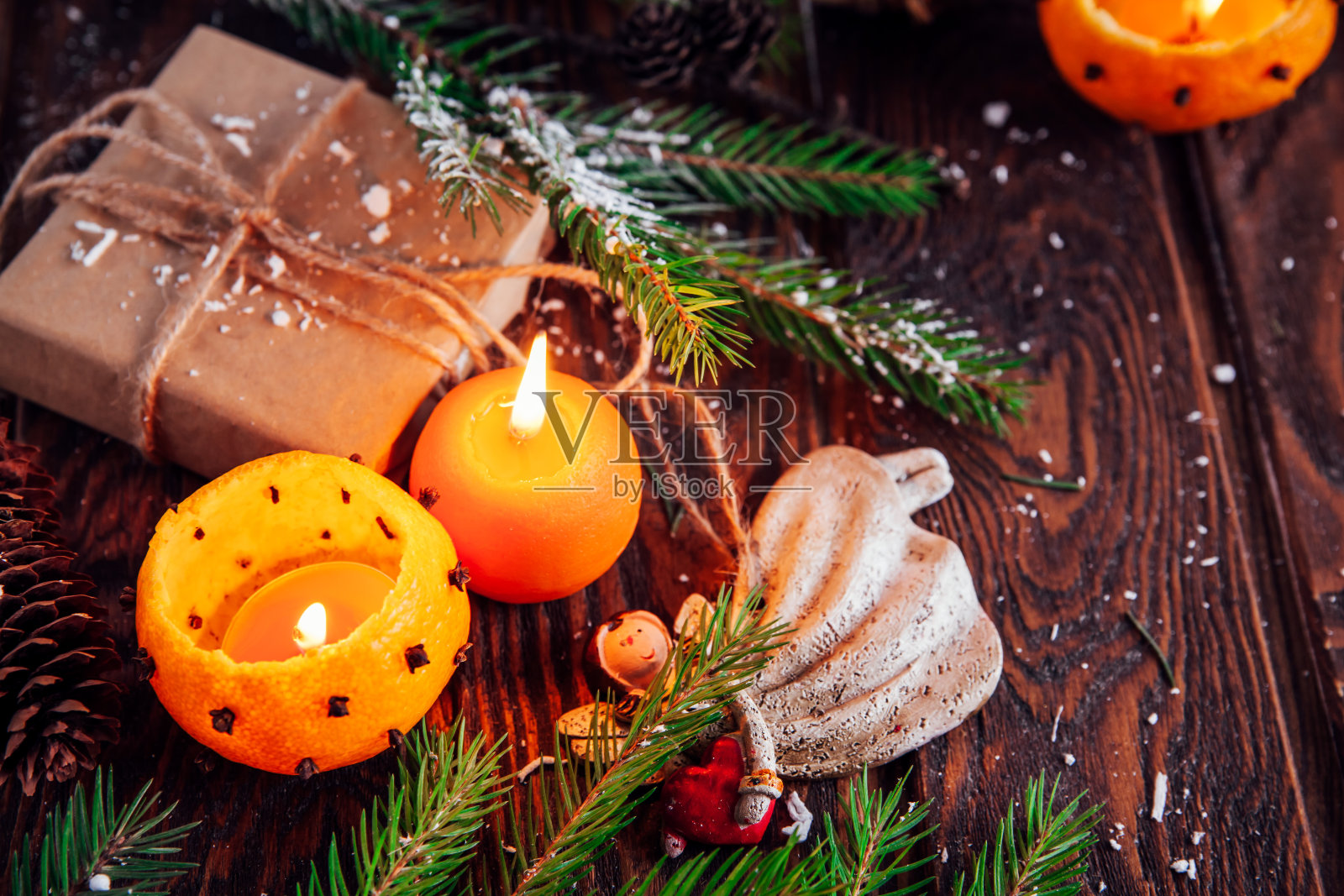 用杉木树枝做成的橘子烛台，木制的桌子上有玩具和礼物。圣诞节和新年的背景。照片摄影图片