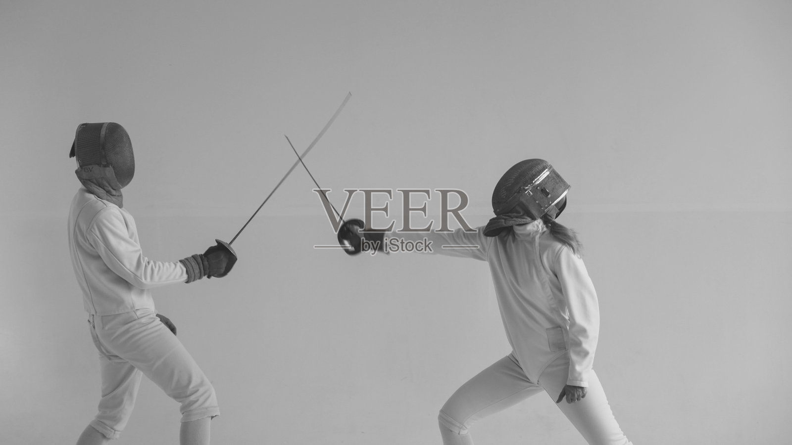 两名击剑运动员在训练后休息，在室内工作室进行击剑攻击练习照片摄影图片