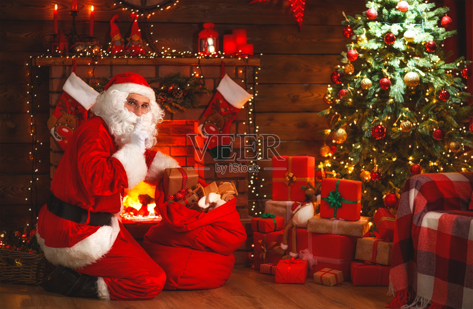 圣诞快乐!圣诞老人靠近壁炉和圣诞树，带着礼物照片摄影图片