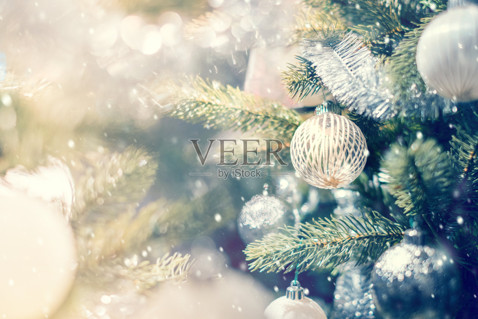 白色和银色的小装饰品挂在装饰好的圣诞树上。照片摄影图片