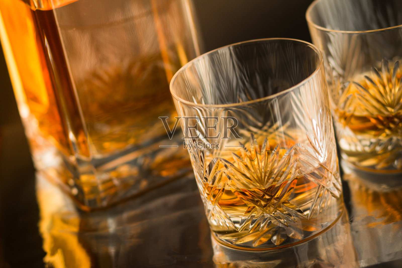 近距离与麦芽苏格兰威士忌在反射吧台与滗水器的背景上的优良水晶玻璃杯照片摄影图片