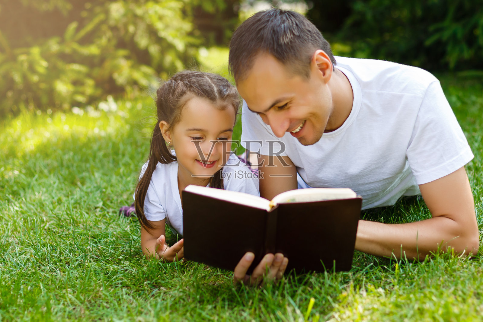 一位年轻的父亲和他的小女儿在读《圣经》照片摄影图片