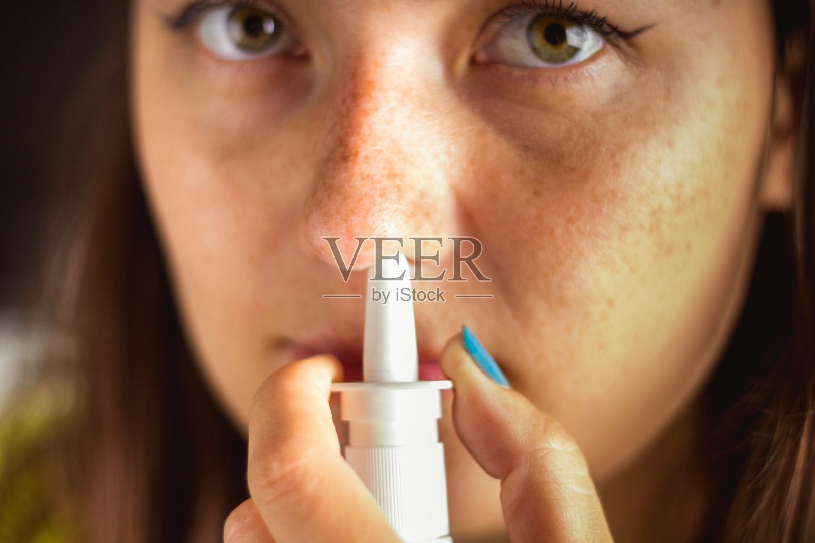 女孩用喷雾剂喷鼻子。治疗感冒流感照片摄影图片