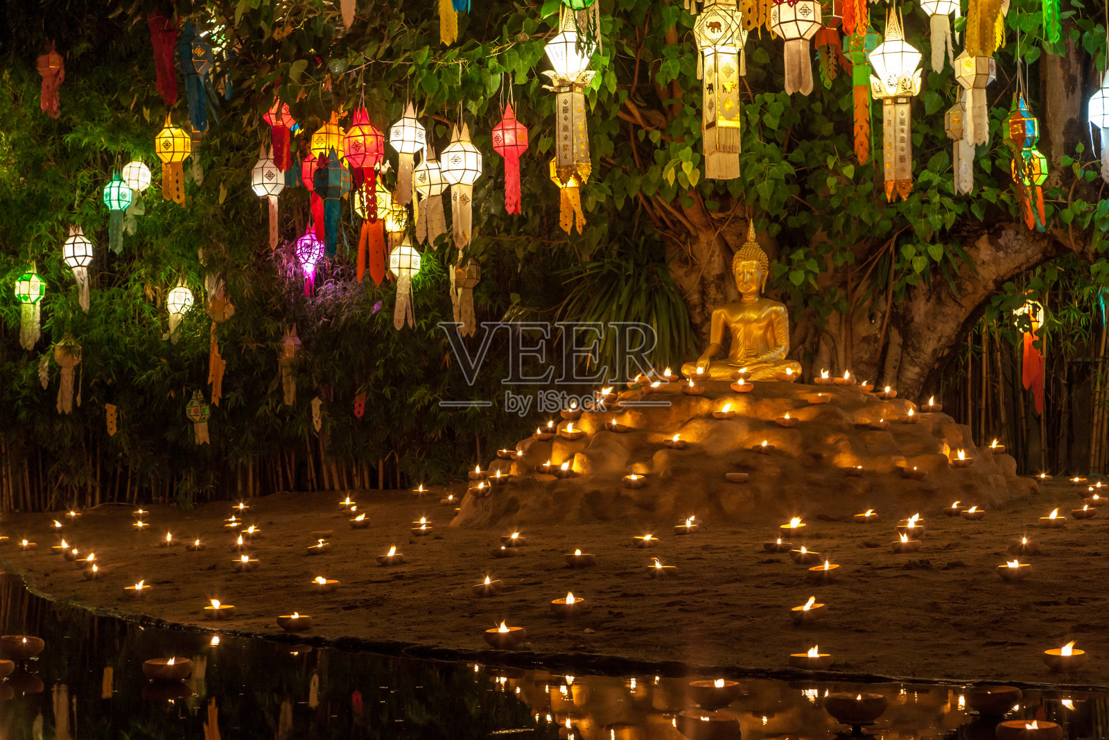 佛像周围是蜡烛和五颜六色的灯笼。照片摄影图片
