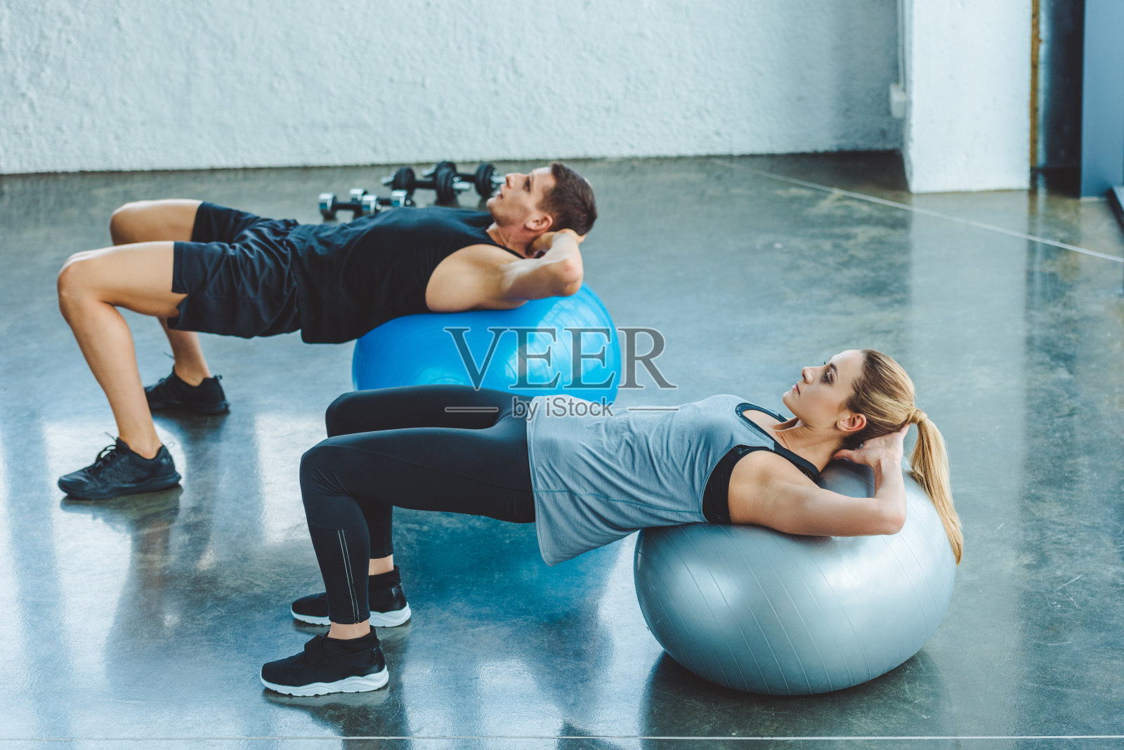 年轻男女在健身房的健身球上锻炼照片摄影图片