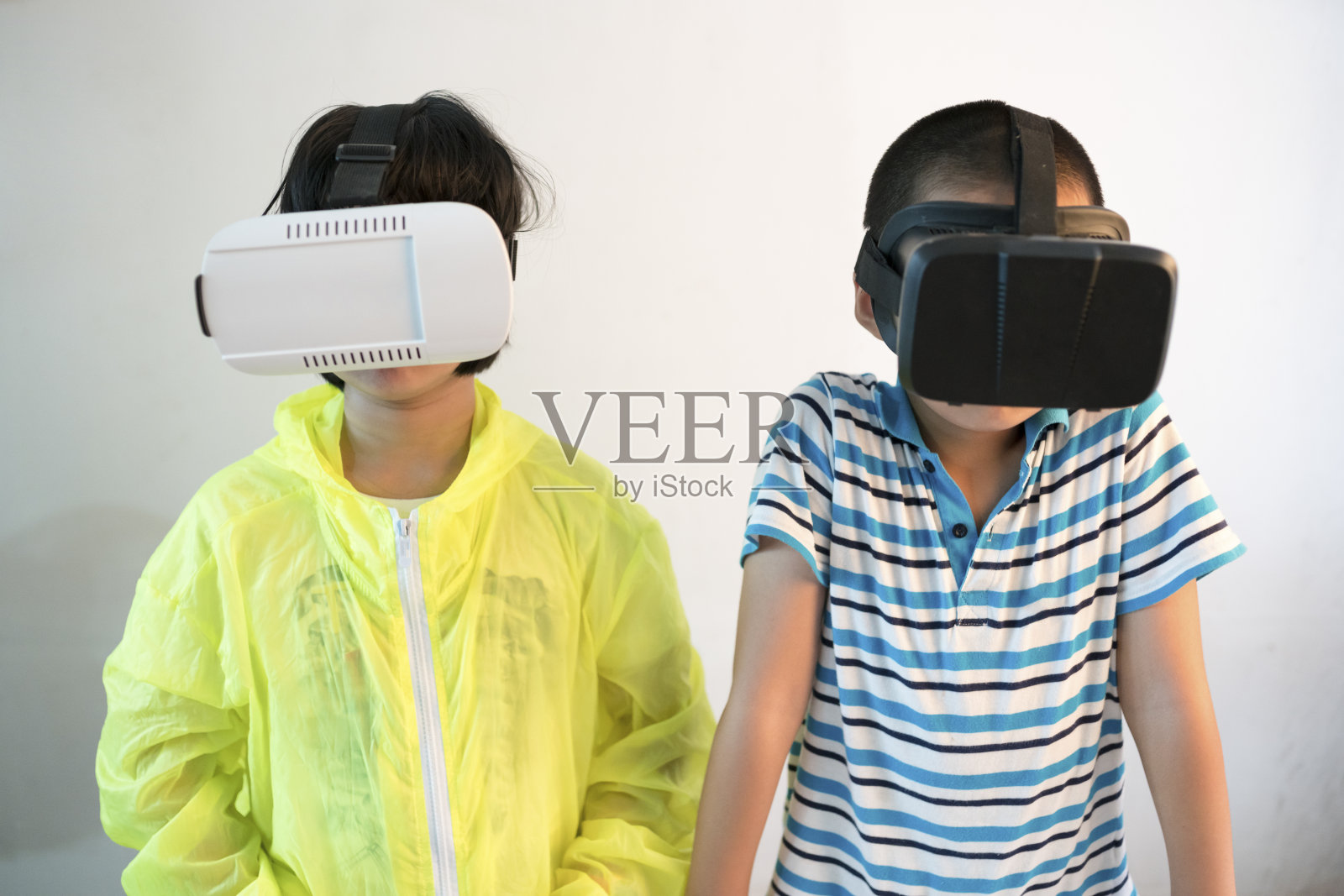 女孩和博尔戴着VR头盔在白墙前玩照片摄影图片