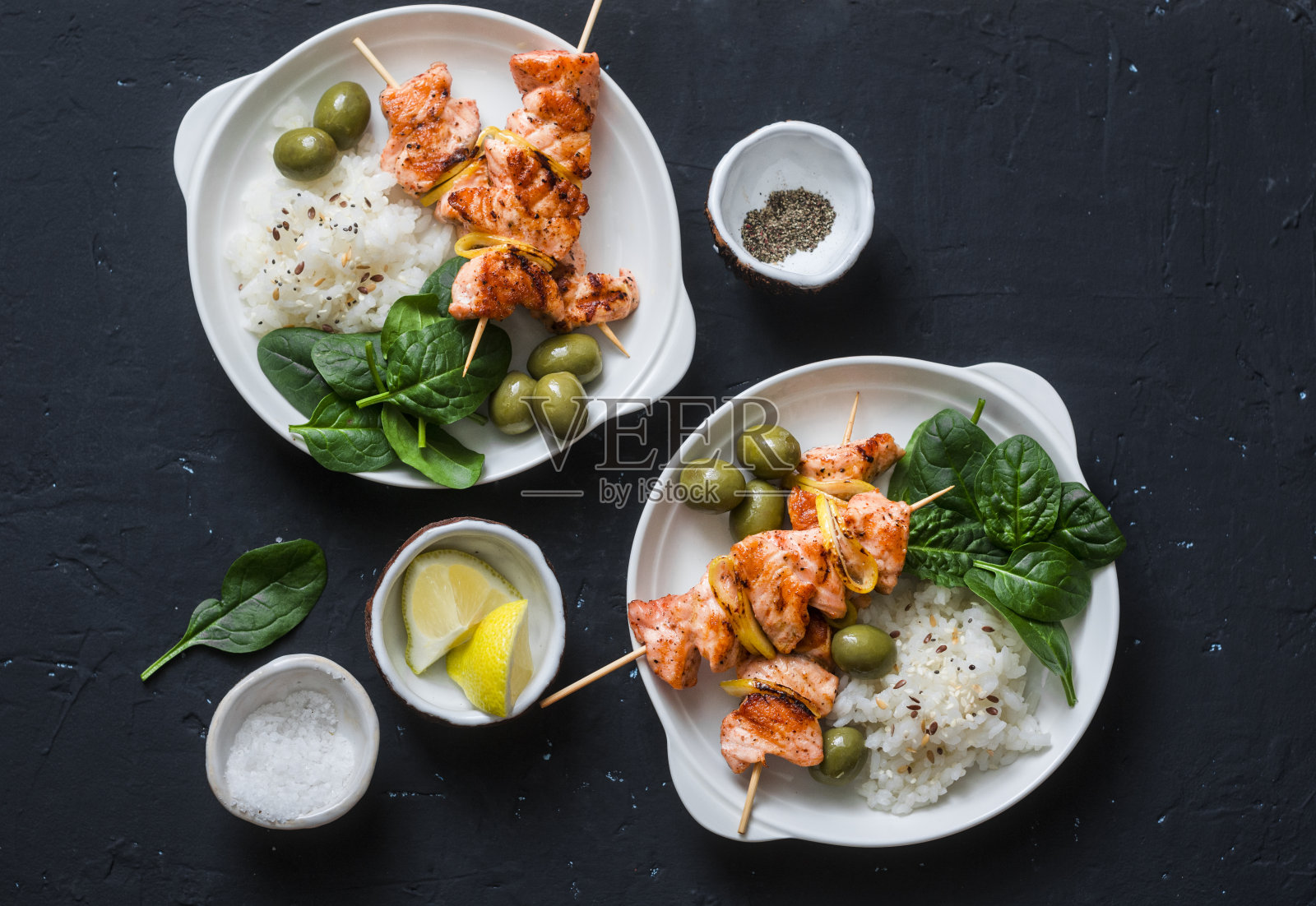 三文鱼串，橄榄，菠菜，米饭——健康的午餐。烤鲑鱼串和配菜在一个黑暗的背景，俯视图照片摄影图片