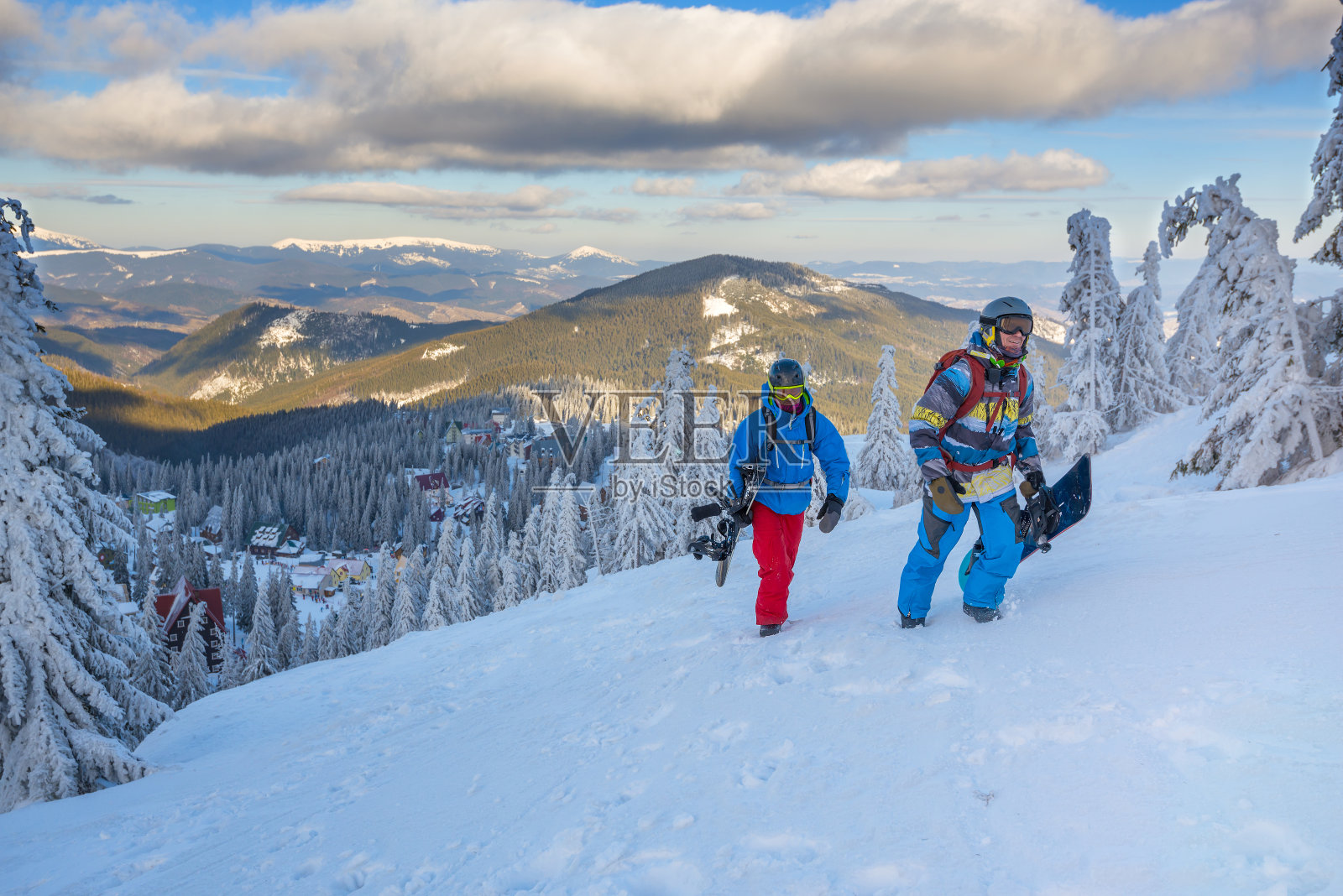 两个快乐的滑雪者，背着背包，在山坡上爬照片摄影图片
