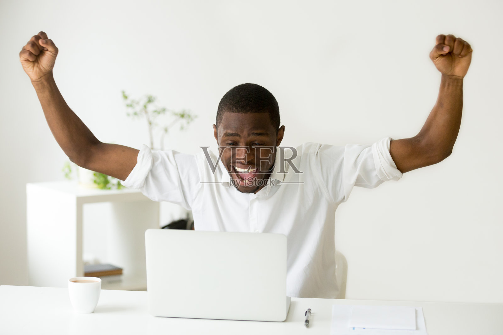 兴奋的非洲赢家看着笔记本电脑庆祝网上胜利照片摄影图片