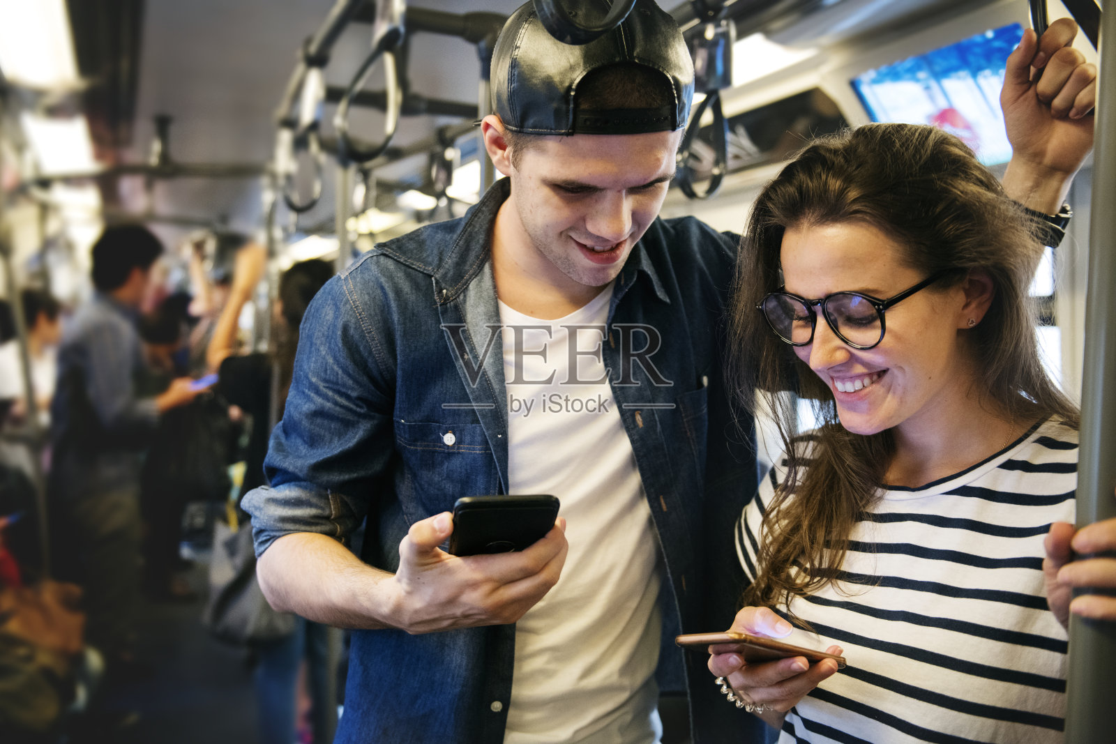 一对可爱的情侣在地铁上玩智能手机照片摄影图片