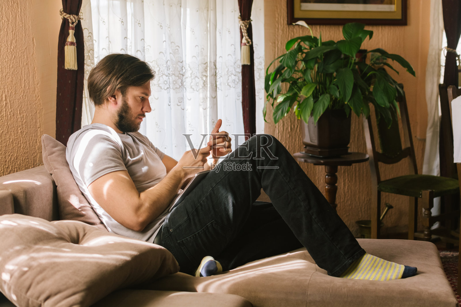 年轻人坐在客厅的沙发上打电话照片摄影图片
