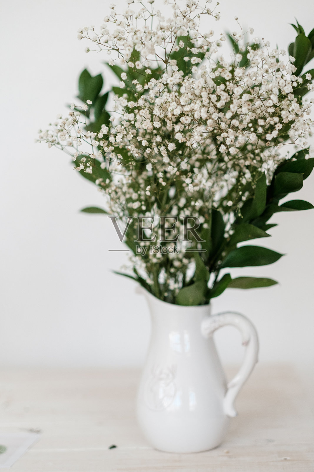 花束吉普赛菲拉在白色的花瓶在白色的桌子上照片摄影图片