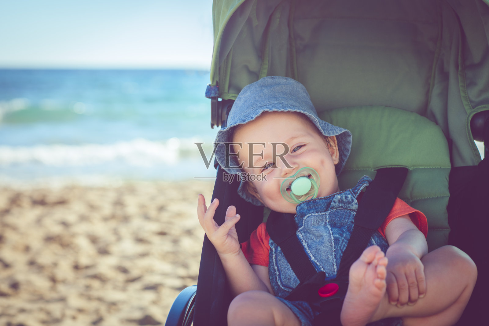 沙滩上婴儿车里的小男孩照片摄影图片