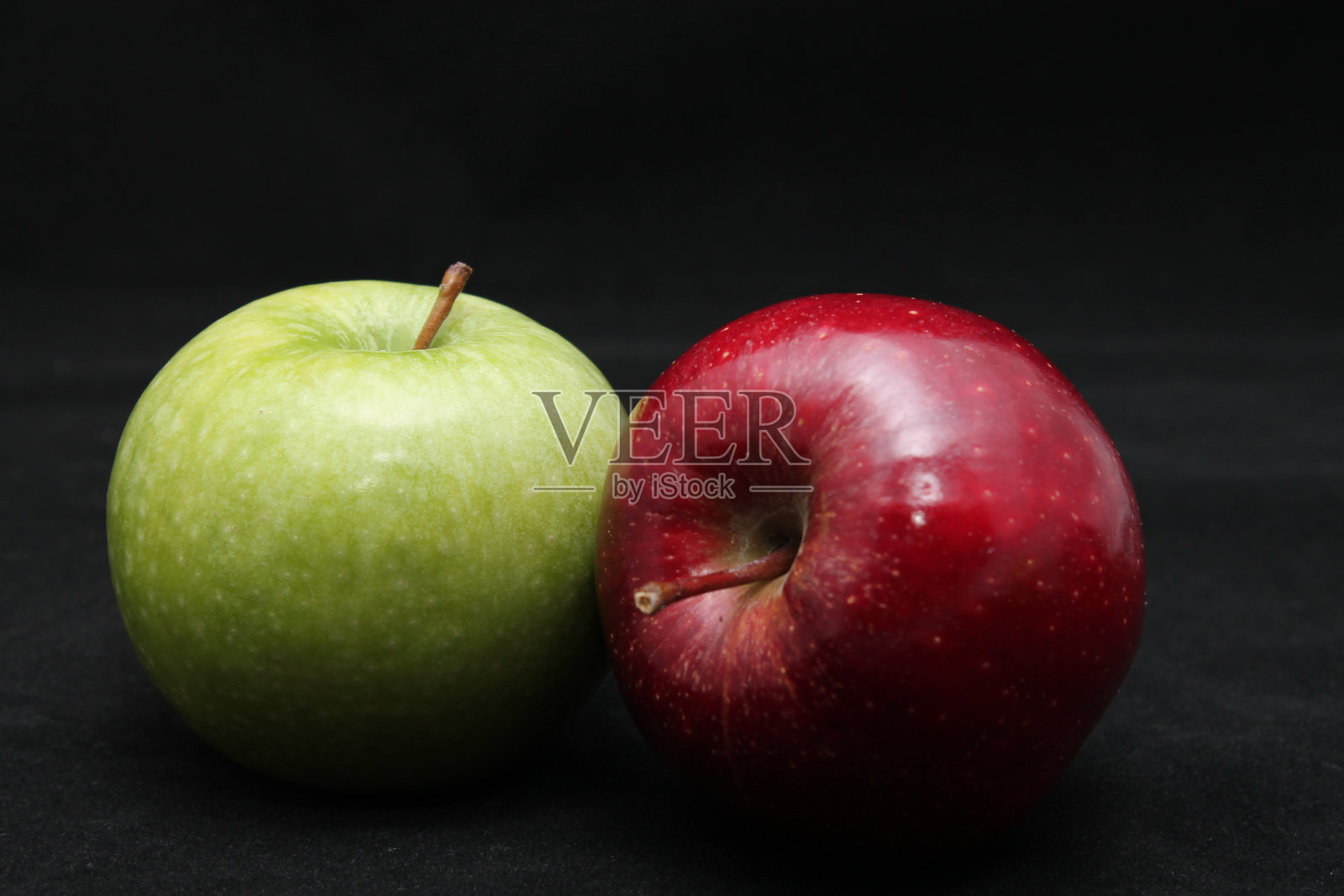 两个绿色和红色的苹果在一个黑色的背景上的特写照片摄影图片