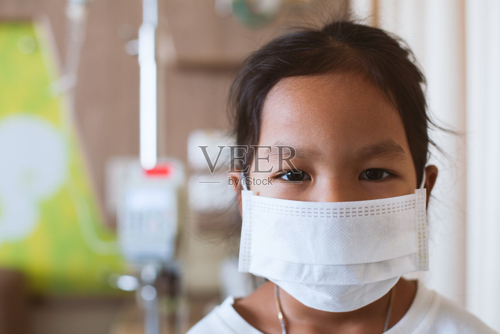 生病的亚洲小女孩住在医院时戴着防护口罩照片摄影图片
