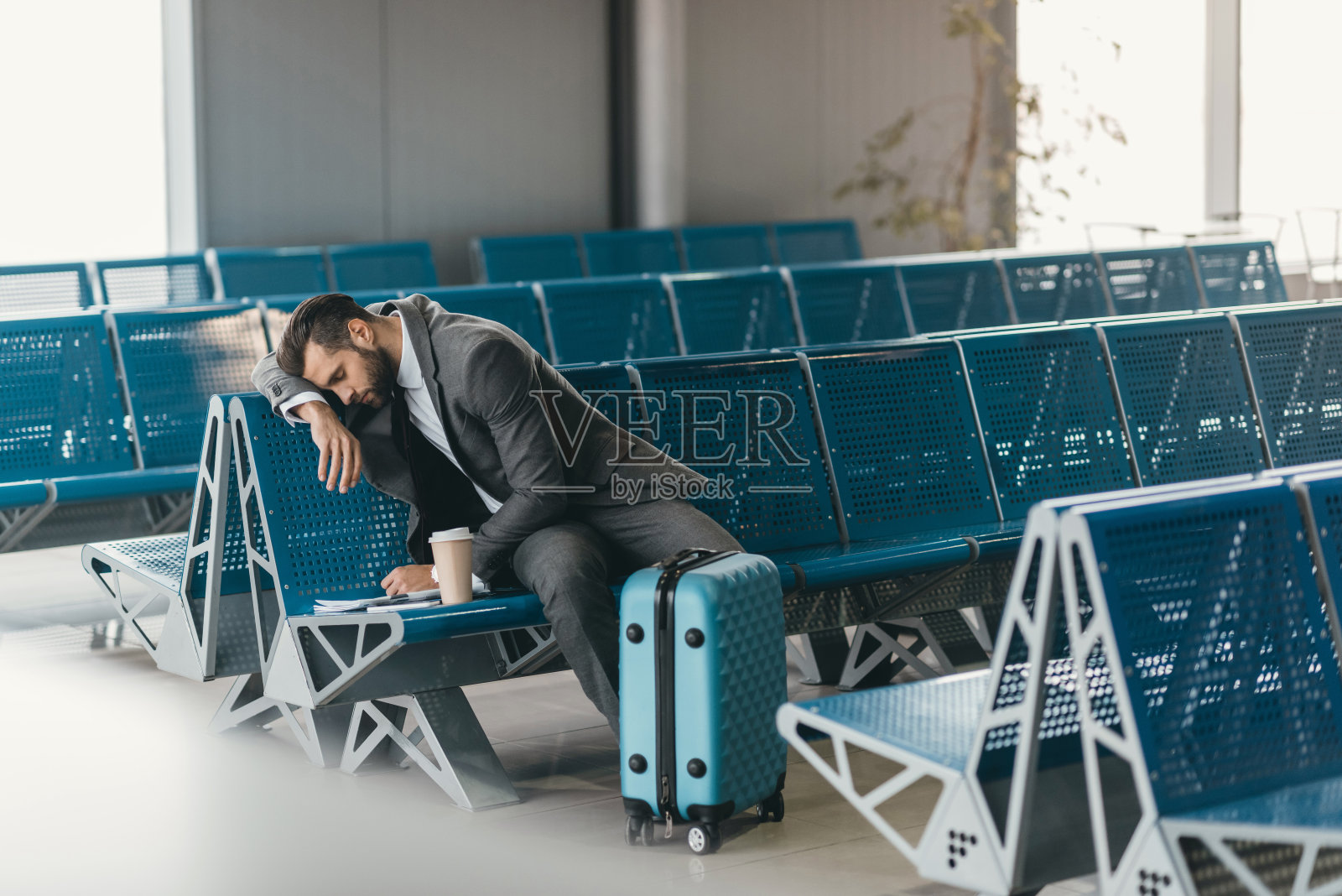昏昏欲睡的年轻商人在机场大厅等待航班照片摄影图片