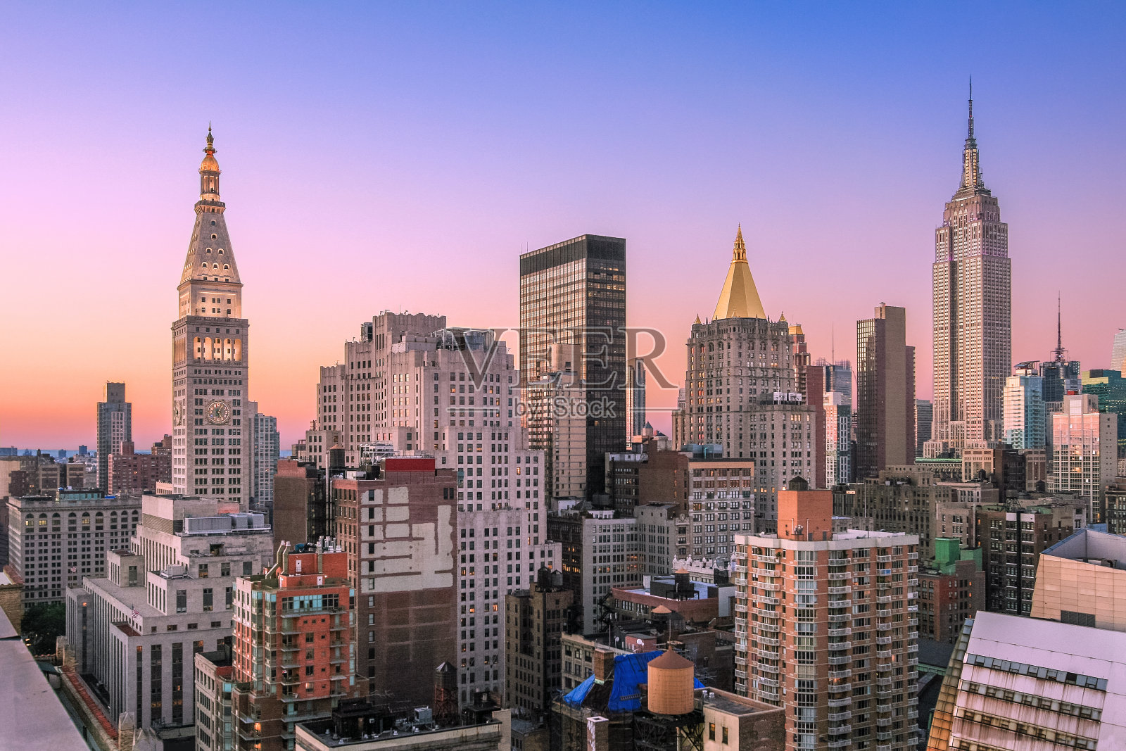 日落时的纽约城市天际线与帝国大厦、大都会人寿保险公司大厦、曼哈顿中城摩天大楼和橙蓝色晴朗的天空。照片摄影图片