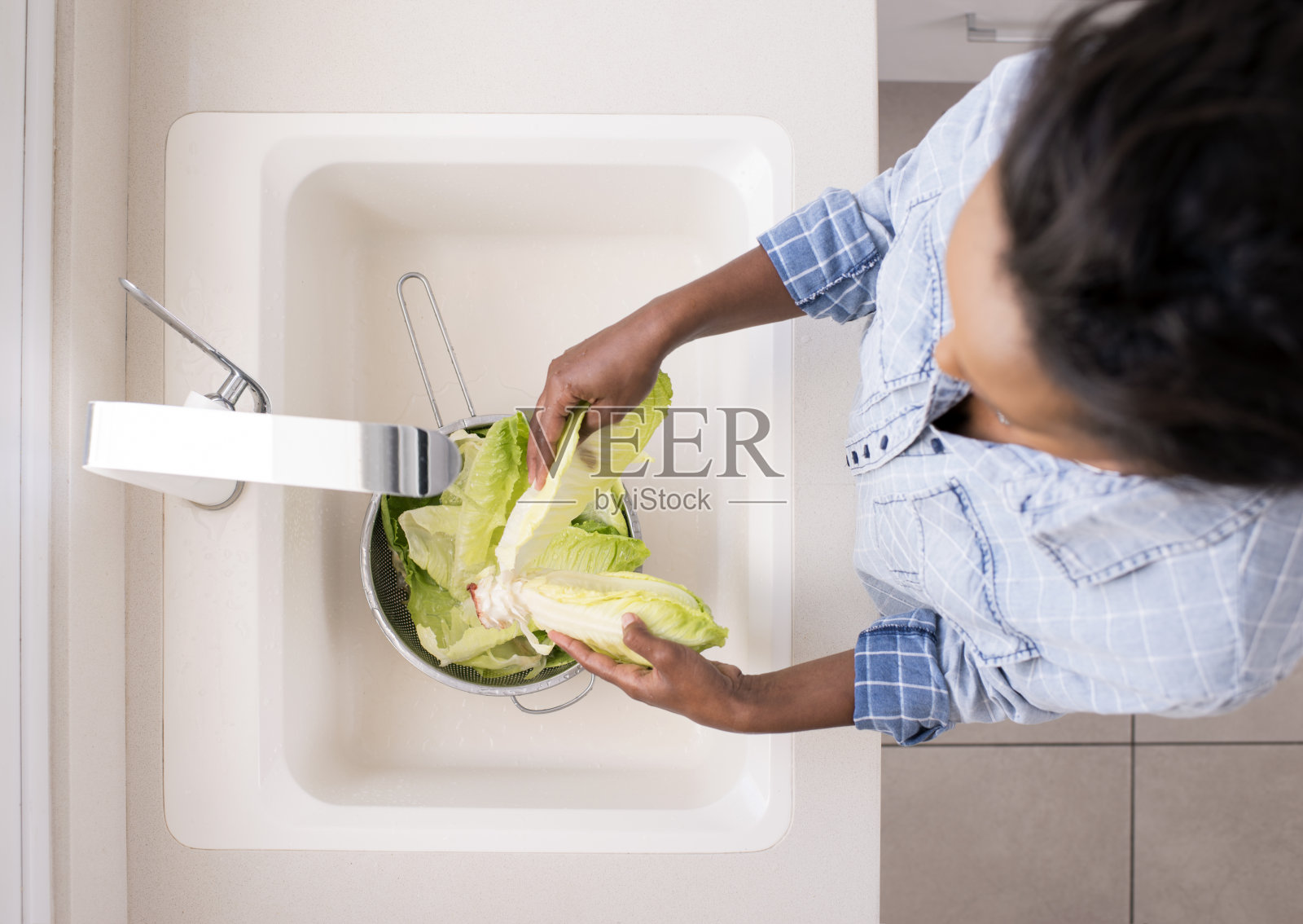 女人清洗生菜的俯视图。照片摄影图片