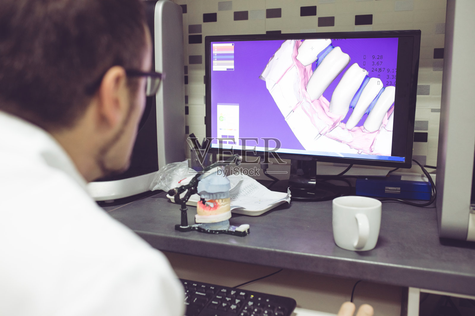 牙科技术员使用电脑操作牙科设备的后视图照片摄影图片