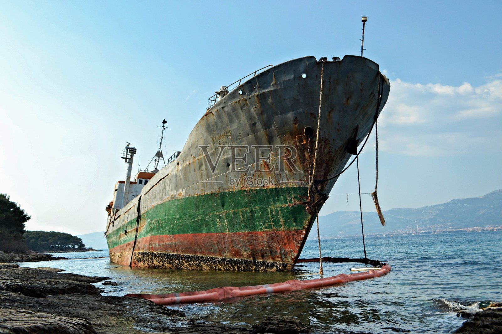 一条被毁坏的老船停在岸边，已经生锈了。照片摄影图片