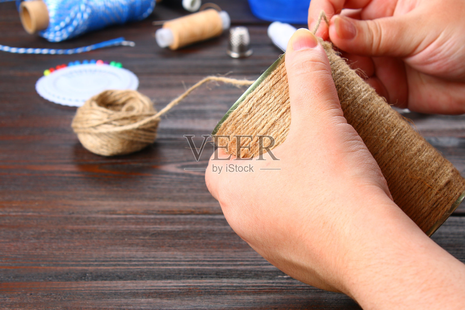 在木桌上用绳子裹着一个铁罐。手工制作的。照片摄影图片