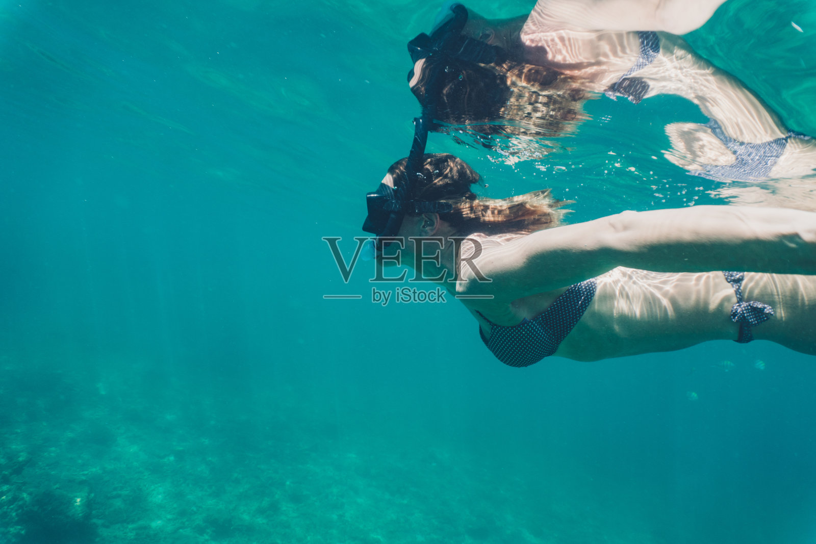 女人在夏天的海里浮潜。照片摄影图片