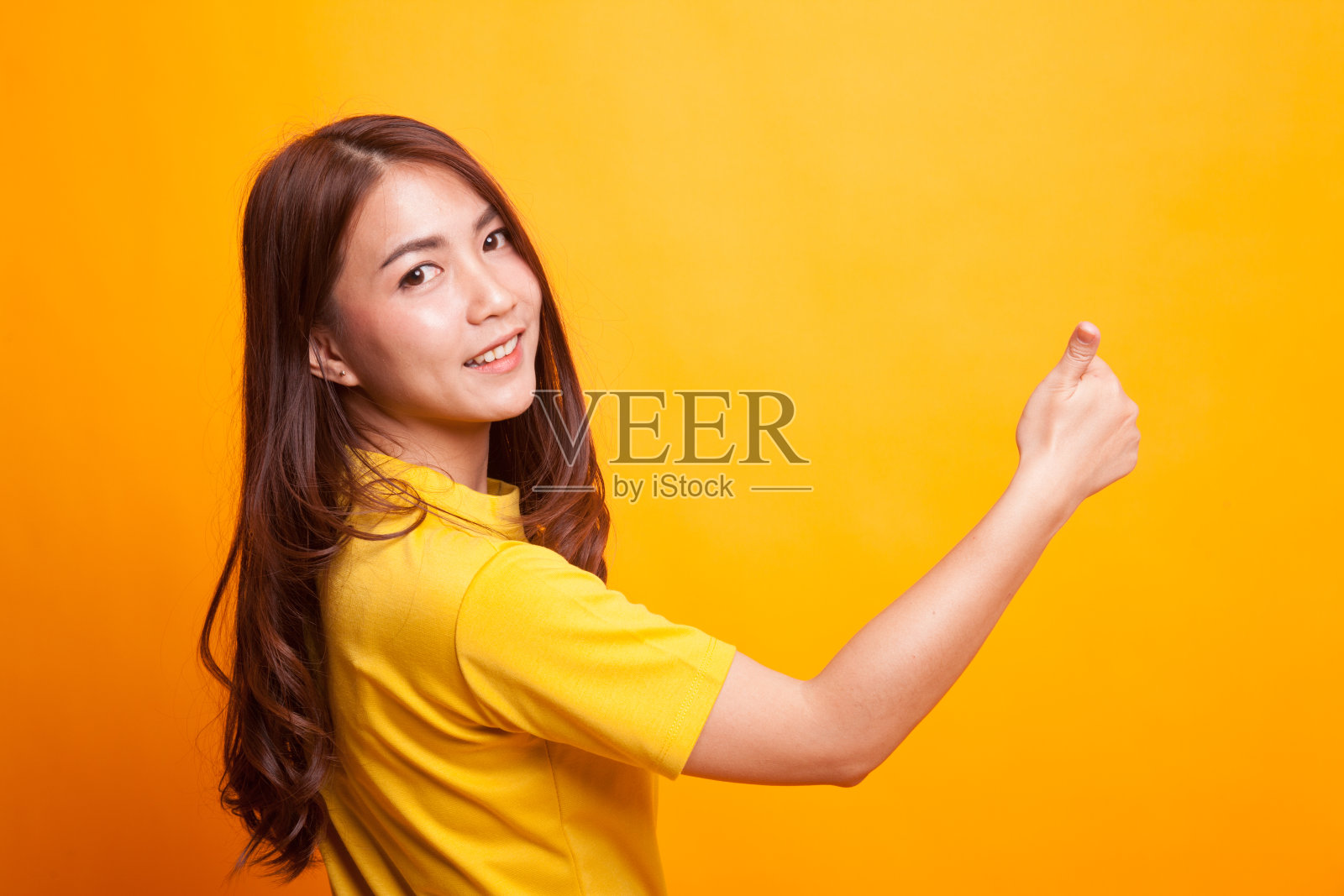 年轻的亚洲女子向后竖起大拇指。照片摄影图片