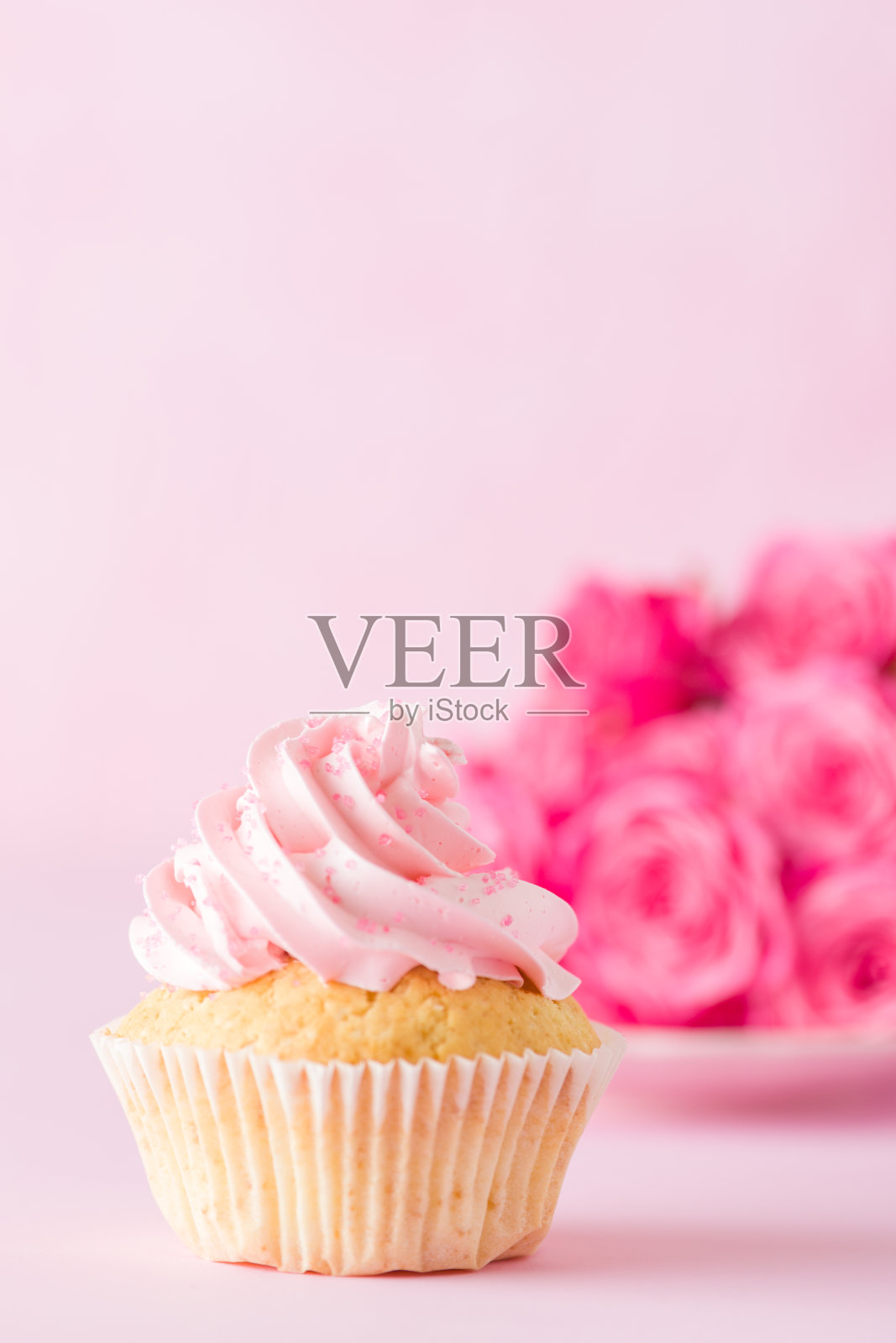 粉奶油装饰和粉红背景上的玫瑰纸杯蛋糕。照片摄影图片