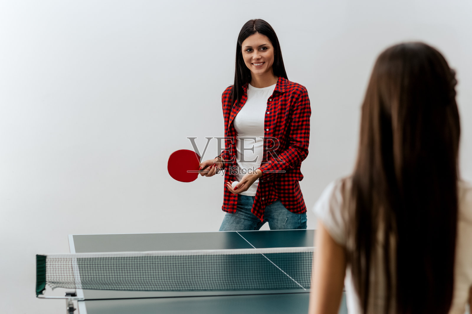 两个漂亮的女孩在打乒乓球。照片摄影图片