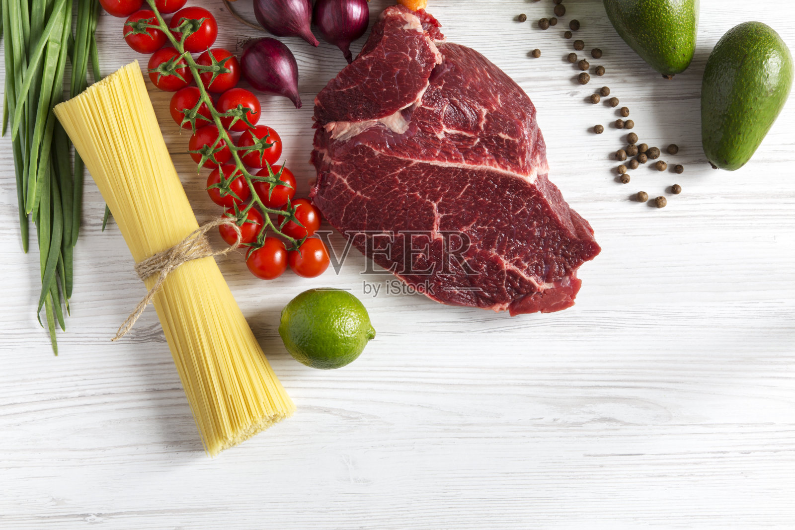 新鲜生肉牛肉配樱桃番茄，意大利面，健康食品。白色木制背景。副本的空间。照片摄影图片