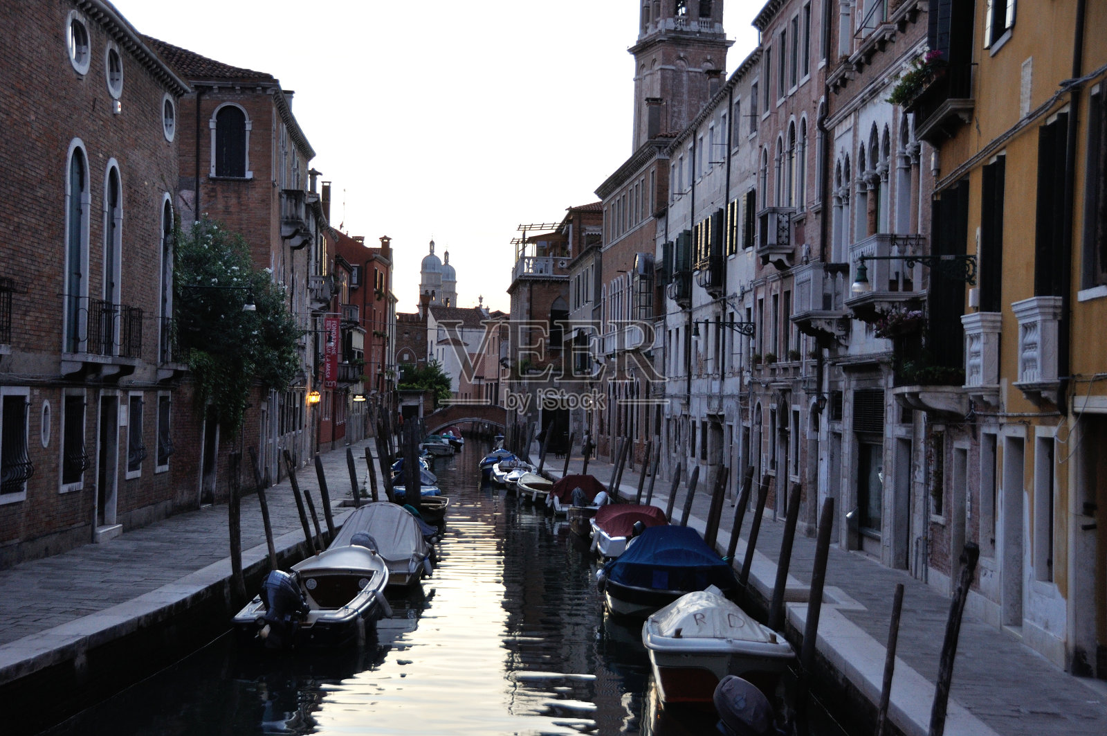 这是威尼斯晚上的典型运河，里面有船只和历史悠久的房屋照片摄影图片