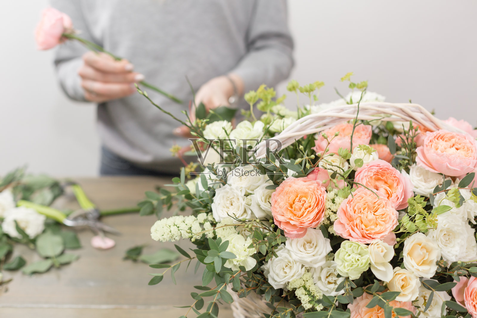 特写手女花匠。花卉车间-女人做一个美丽的花组成一束在柳条篮子。花卉栽培技术概念照片摄影图片