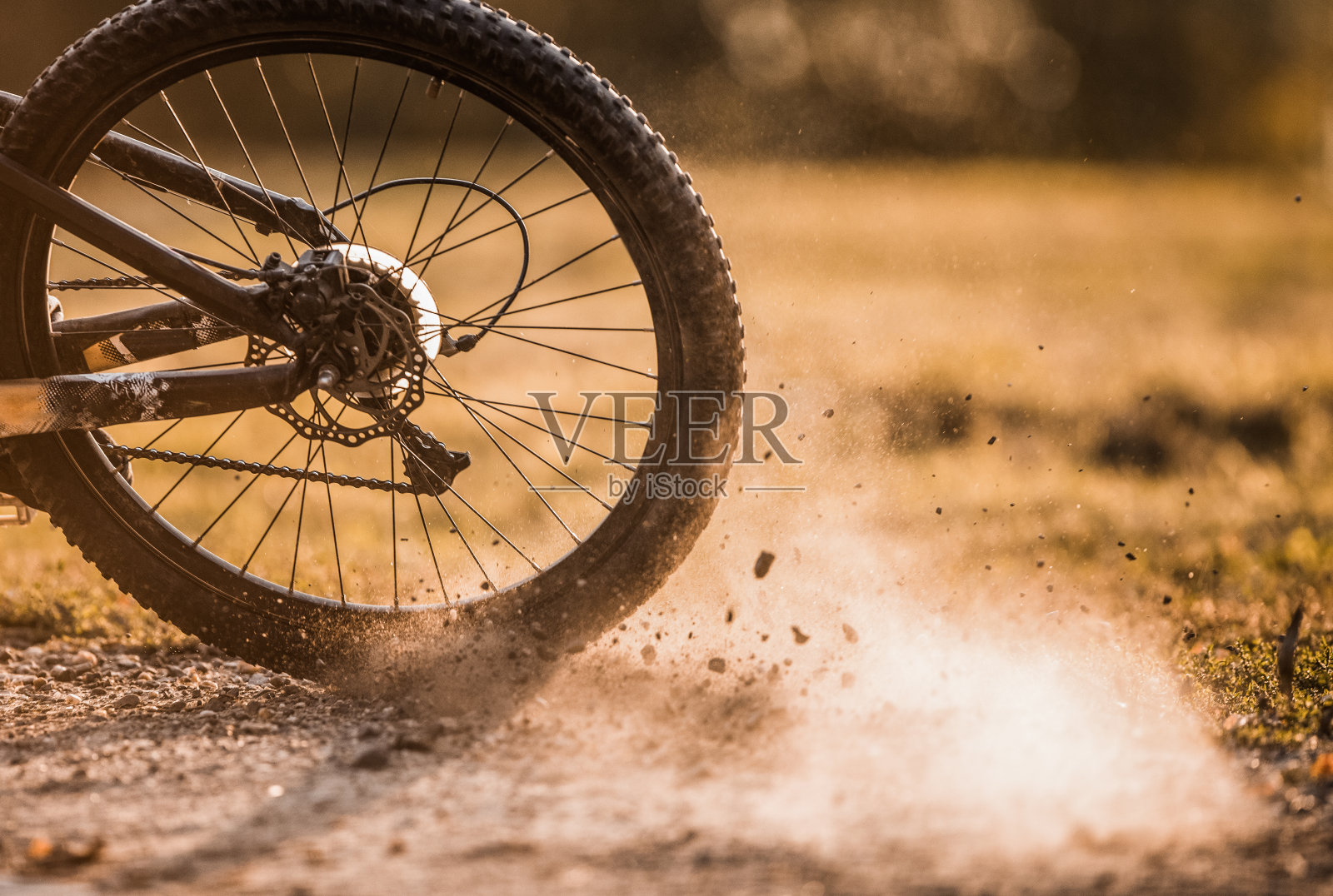 在泥土路上转动的自行车轮子。照片摄影图片