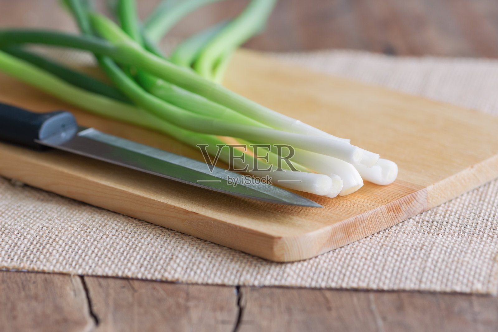 把新鲜的葱和菜刀放在木板上，放在有拷贝空间的木桌上。准备大葱做家常菜。食物和蔬菜概念的背景或壁纸。照片摄影图片