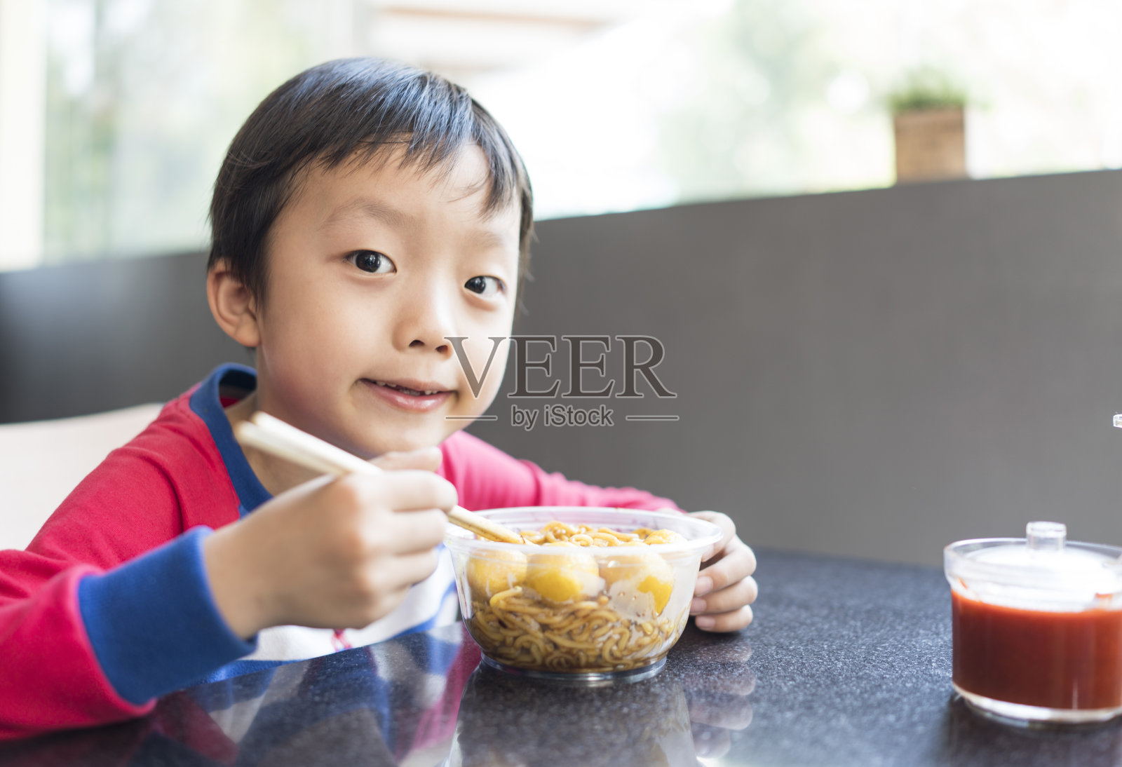 亚洲小孩用筷子吃美味的面条照片摄影图片