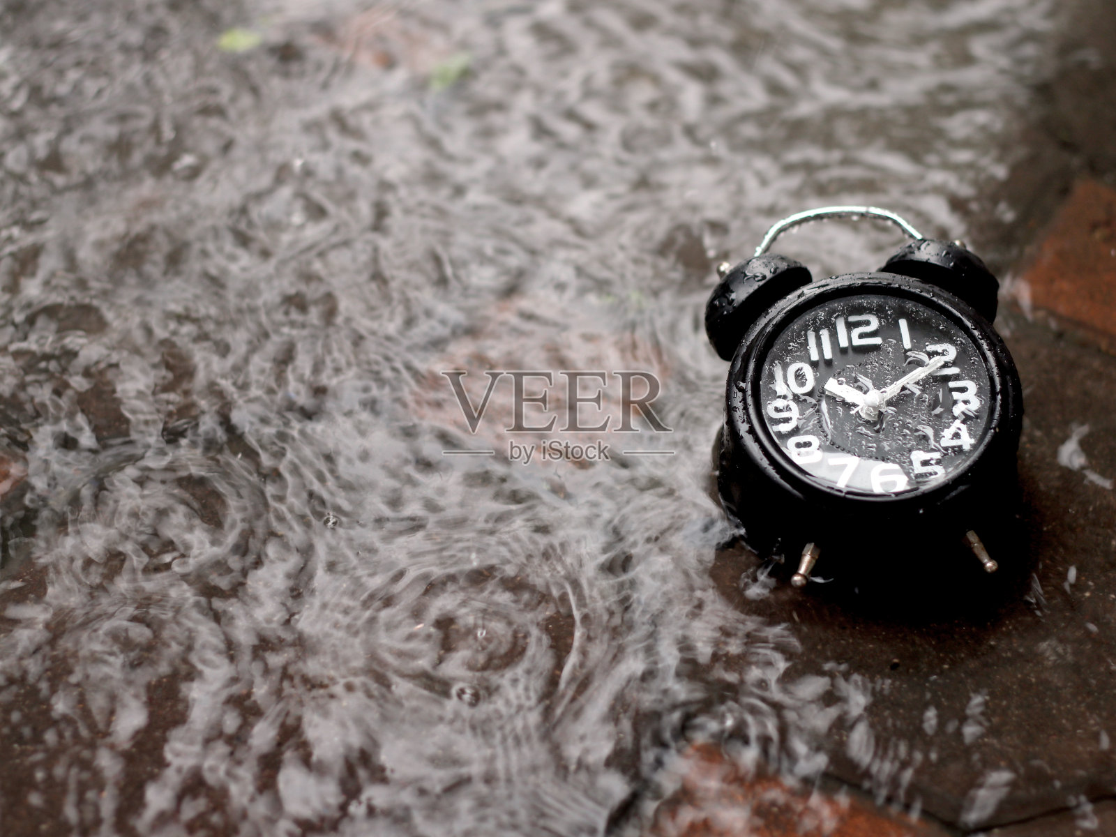 经典的黑色制高点闹钟在雨中的水照片摄影图片