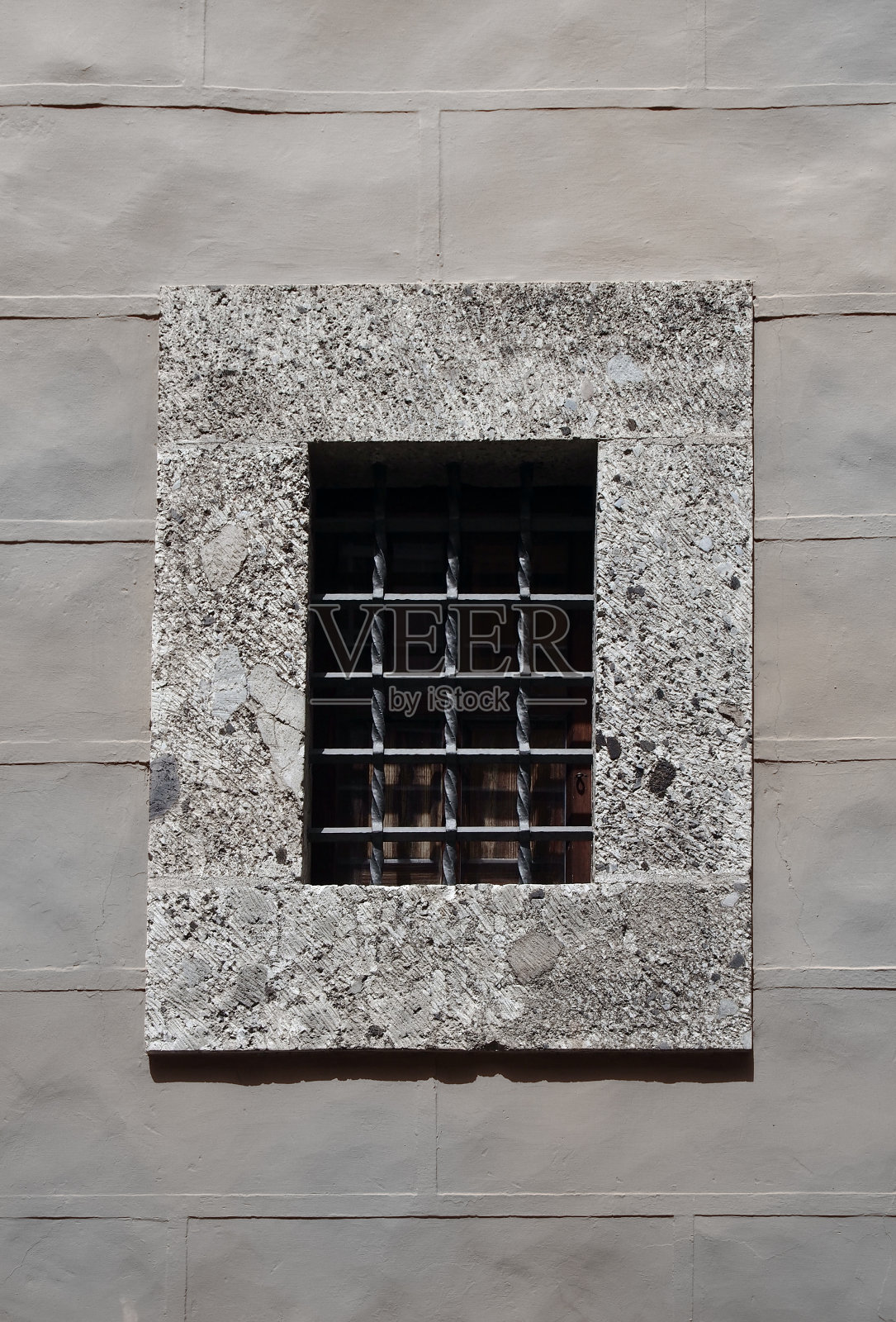 灰色的石墙上有一扇混凝土窗户，上面有厚厚的安全金属条照片摄影图片