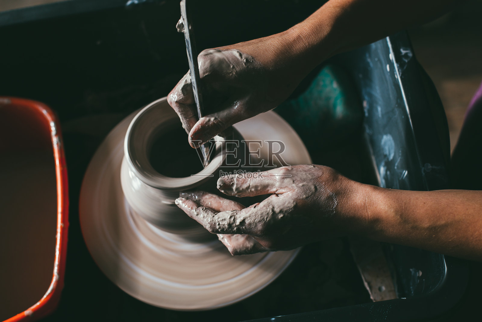 创造一个罐子或花瓶的白色粘土特写。主缸。手工制作陶罐宏。车间里的雕刻家用陶器制作了一个瓦罐。扭曲的陶工旋盘。照片摄影图片