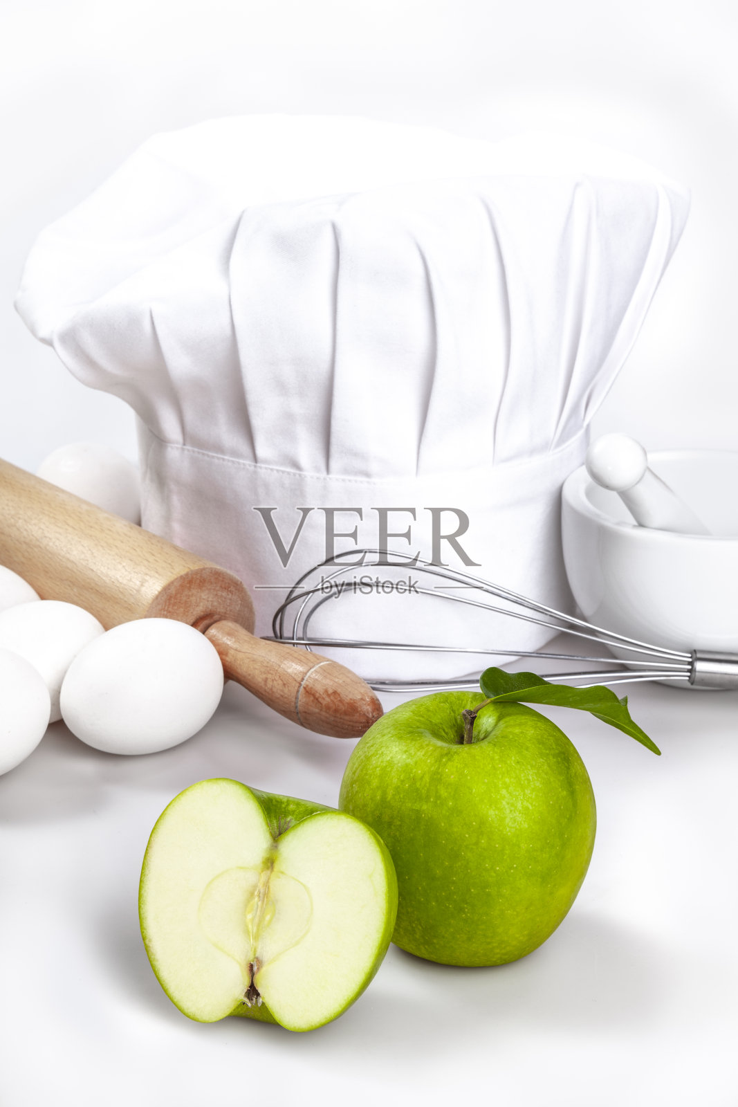 厨师帽和新鲜的苹果在白色的桌子上。照片摄影图片
